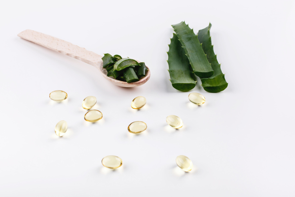 wooden-spoon-with-aloe-lies-white-table-with-golden-capsules-with-oil (1).jpg